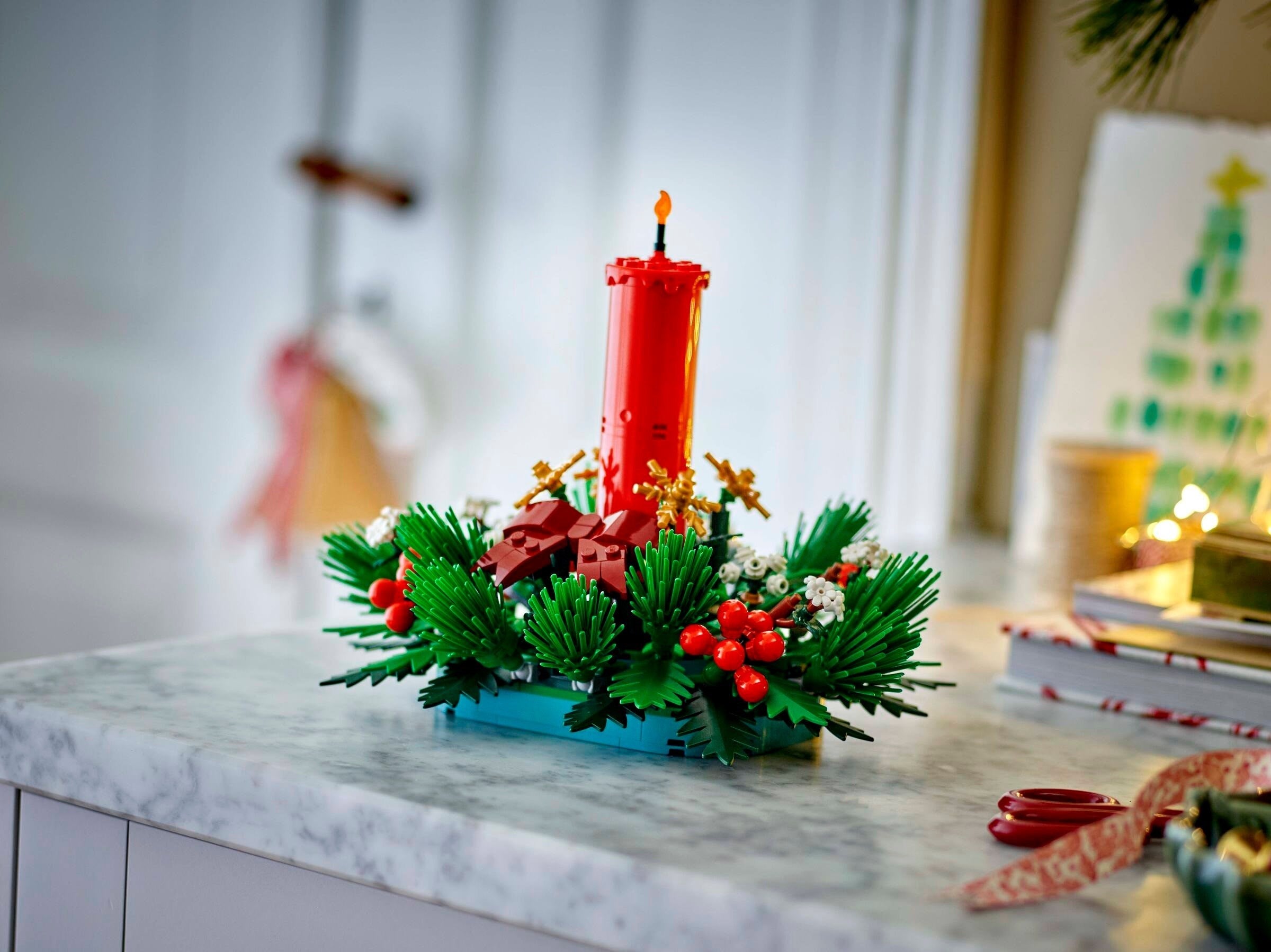 Decorative Christmas arrangement with a red candle on a marble surface.